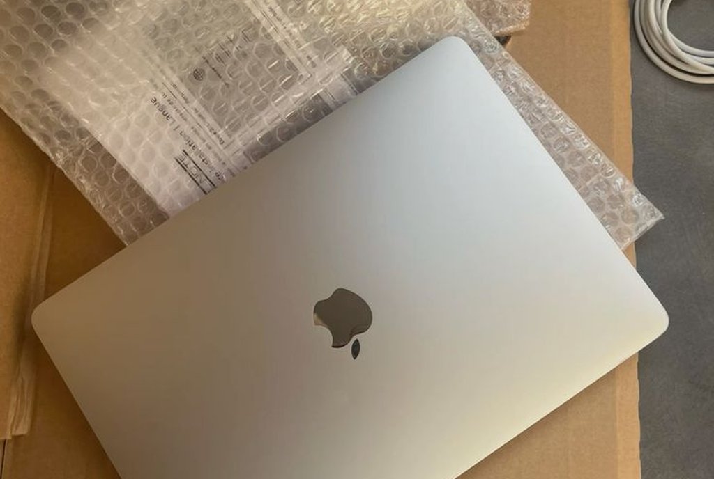 Notebook prateado dentro de uma caixa de papelão com plástico bolha